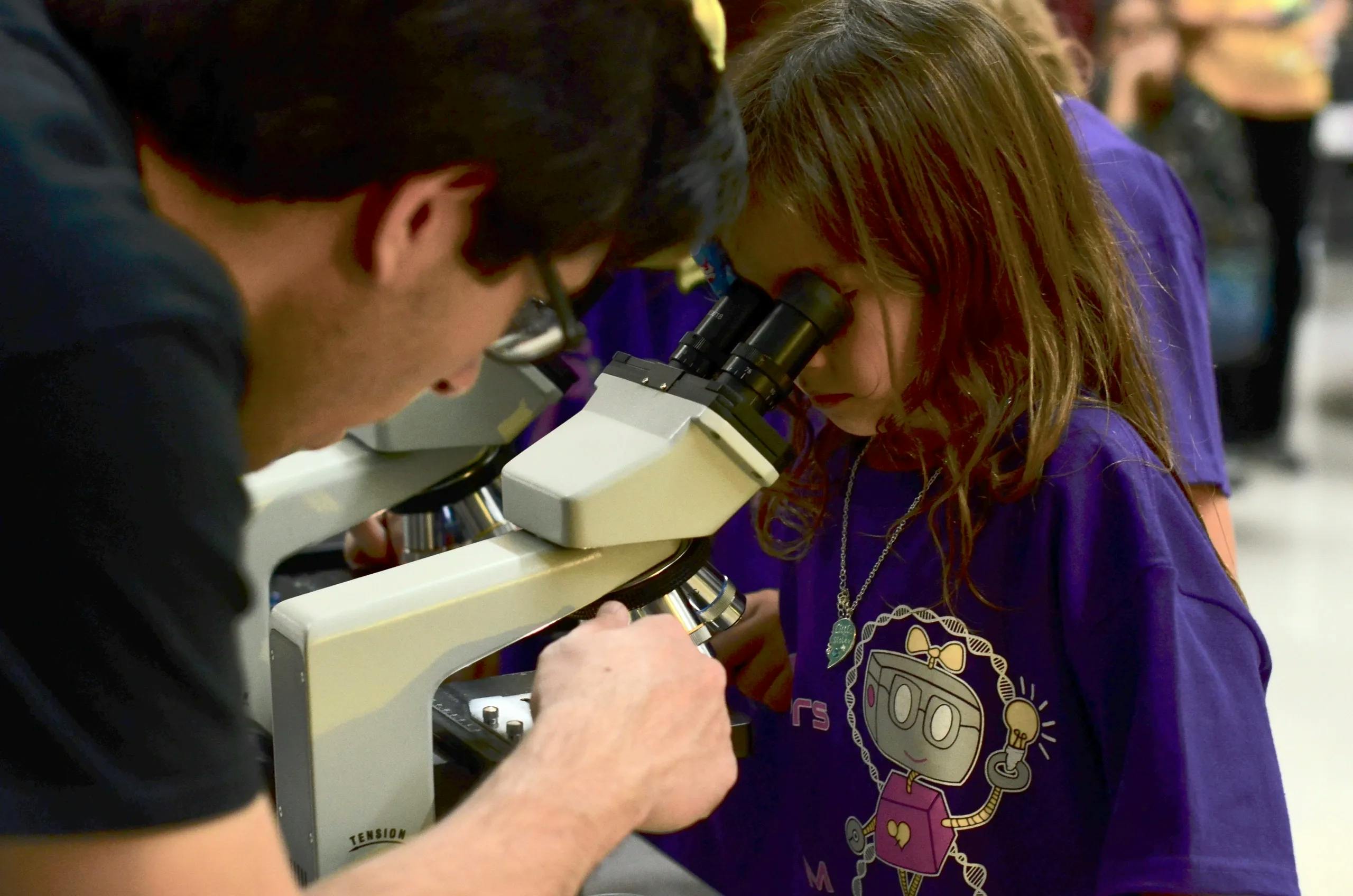Young girl looking through microscope during an experiment at a SiS event